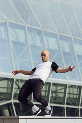 Sportlicher Mann macht Parkour-Gleichgewichtsübungen im Freien in einer städtischen Szene - ADSF38069
