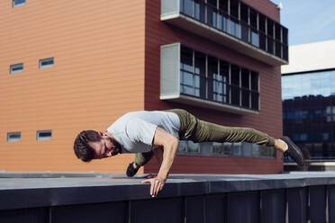 Athletic man doing parkour exercises outdoors - ADSF38072