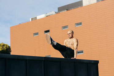 Sportlicher Mann macht Parkour-Gleichgewichtsübungen im Freien in einer städtischen Szene - ADSF38074