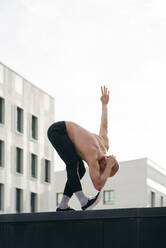 Athletic man doing parkour balance exercises outdoors in urban scene - ADSF38076