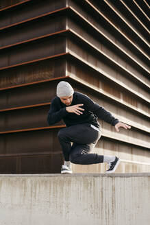 Sportlicher Mann macht Parkour-Gleichgewichtsübungen im Freien in einer städtischen Szene - ADSF38079
