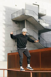 Athletic man doing parkour balance exercises outdoors in urban scene - ADSF38080