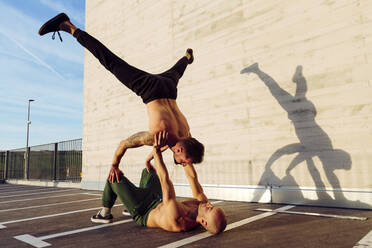 Young athletic shirtless men doing an urban workout outdoors practicing balance exercises - ADSF38090