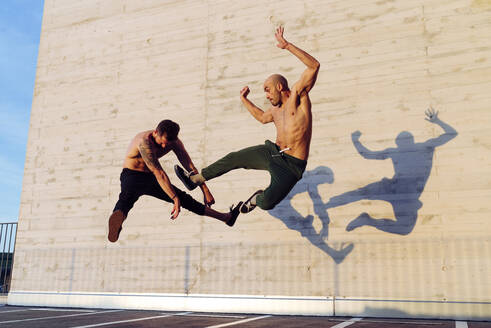 Sportliche Männer ohne Hemd kämpfen in einem spektakulären Kampfsportkampf im Freien - ADSF38095