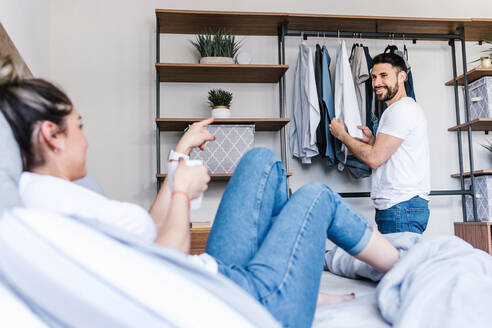 Inhalt Lateinisches Paar, das gemeinsam zu Hause im Schlafzimmer Kleidungsstücke auf Kleiderbügeln im Schrank auswählt - ADSF38174