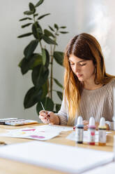 Young girl painting watercolor drawings at home - ADSF38206