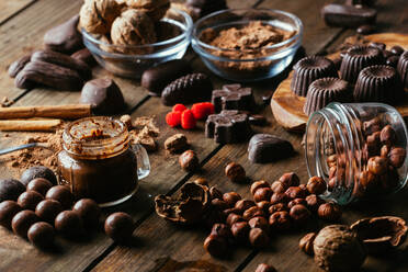 Various handmade chocolates with nuts arranged on wooden table with peanut butter and cinnamon sticks - ADSF38256