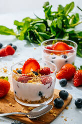 From above delicious homemade yogurt with strawberries, berries and cereals on white background - ADSF38264