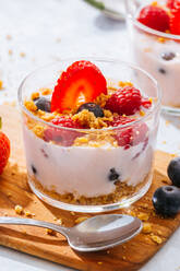 Close up of delicious homemade yogurt with strawberries, berries and cereals on white background - ADSF38265