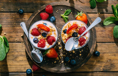 From above top view of delicious homemade yogurt with strawberries, berries and cereals on wooden table background - ADSF38266