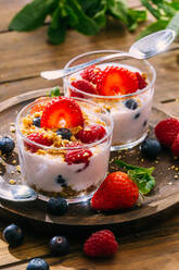 Delicious homemade yogurt with strawberries, berries and cereals on wooden table background - ADSF38267