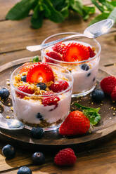 Leckere hausgemachte Joghurt mit Erdbeeren, Beeren und Getreide auf Holztisch Hintergrund - ADSF38267