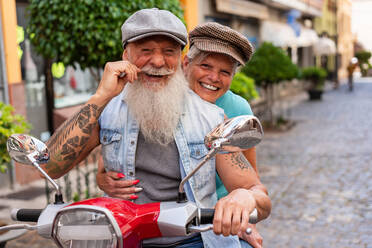 Frontansicht eines modernen älteren Paares auf einem Motorrad während der Fahrt durch die Stadt - ADSF38285