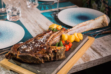 Leckeres gegrilltes Ribeye-Rindssteak mit Salzkörnern und leuchtend roten und gelben Tomaten auf dem Tisch serviert - ADSF38409