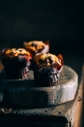 Leckere Muffins mit Schokoladenstückchen auf dunklem Holzhintergrund - ADSF38410