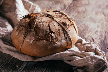 Von oben köstliches, frisch gebackenes Brot auf einem alten Schneidebrett auf einem Holztisch in der Küche - ADSF38414