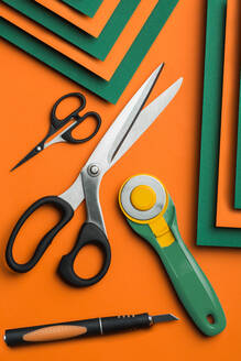 Scissors and cutter on green and orange cardboard background - ADSF38419