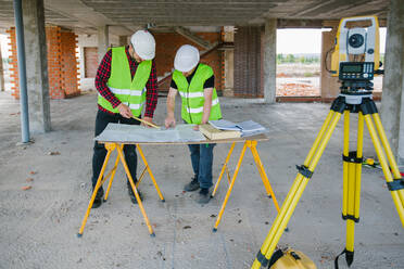 Vermessungsingenieur bei der Arbeit auf der Baustelle mit Messgeräten (Totalstation) - ADSF38435