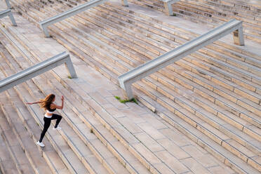 High angle side view of unrecognizable fast runner in activewear jogging on city staircase during workout - ADSF38443
