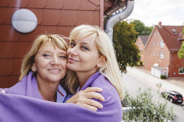 Glückliche Mutter und Tochter in eine Decke eingewickelt auf dem Balkon stehend - IHF01265