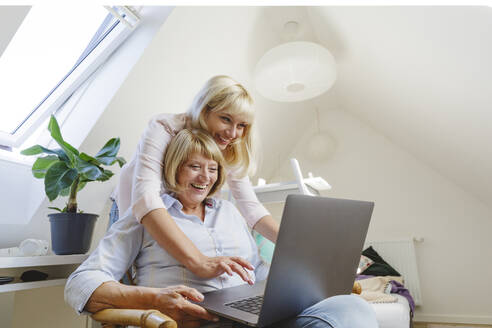 Glückliche blonde Frau mit Mutter, die zu Hause einen Laptop benutzt - IHF01277