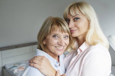 Smiling blond woman embracing and caring mother at home - IHF01297
