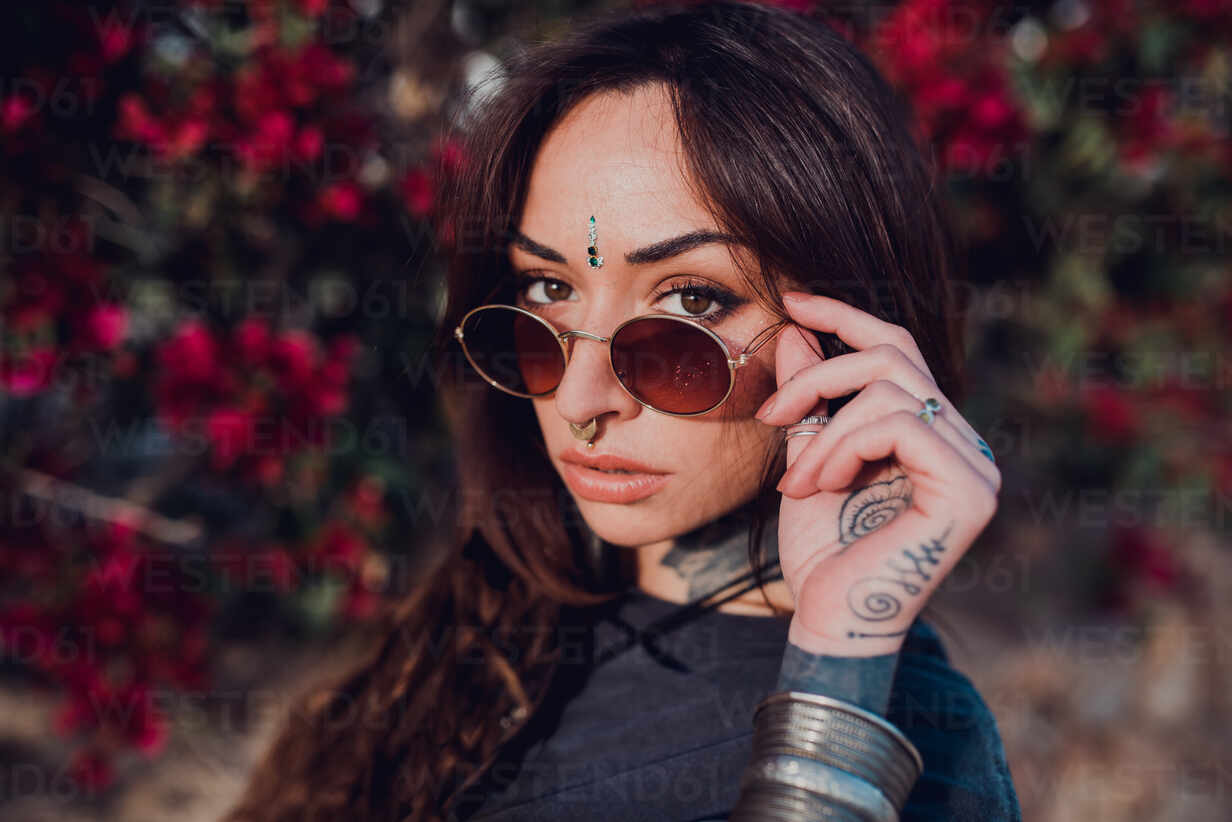 Portrait of young woman with nose piercing and tattoos sitting on balcony  at backlight, Stock Photo, Picture And Royalty Free Image. Pic.  WES-GIOF04602 | agefotostock