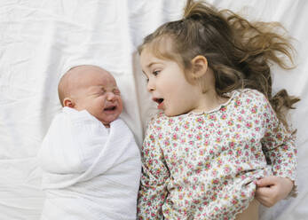 Overhead view of girl (2-3) with newborn (0-1 months) brother on bed - TETF01754