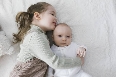 Girl (2-3) embracing newborn (0-1 months) brother on bed - TETF01761