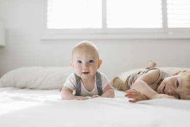 Portrait of brothers (6-11 months, 2-3) lying on bed - TETF01794