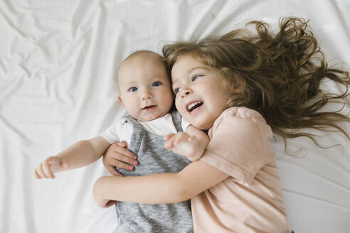 Mädchen (2-3), das seinen kleinen Bruder (6-11 Monate) umarmt - TETF01797