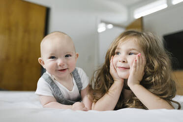 Siblings (2-3, 6-11 months) lying on bed - TETF01799