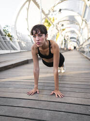 Young sportswoman practicing push-ups on footpath - AMRF00029