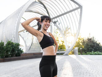 Happy young woman flexing muscles standing on footpath stock photo