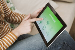 Nahaufnahme einer Frau, die ein digitales Tablet mit einer Smart-Home-App verwendet - EBBF06411
