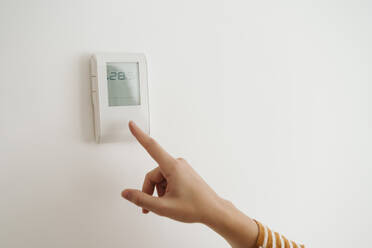 Finger touching thermostat on the wall - EBBF06450