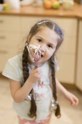 Portrait of little girl licking whipped cream off wire whisk - ONAF00016