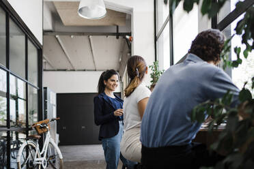 Happy young businesswoman talking with colleagues in office - DCRF01362