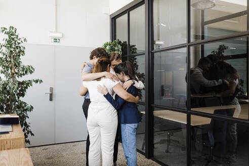 Business people huddling each other in circle at office - DCRF01366