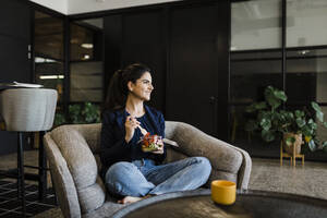 Smiling businesswoman having fruits in cafeteria at workplace - DCRF01378