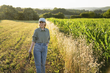 Woman standing in field holding digital tablet - EKGF00062