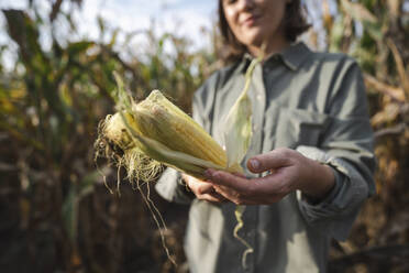 Woman holding corncob in field - EKGF00098