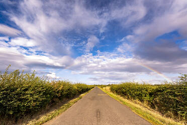 Vereinigtes Königreich, Schottland, Regenbogen, der sich gegen die über der Landstraße schwebenden Wolken wölbt - SMAF02223