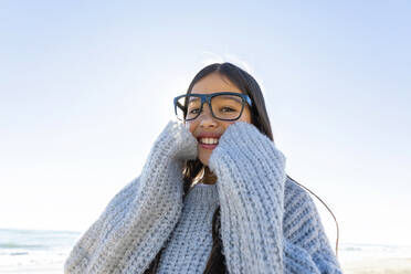 Glückliches Mädchen mit Pullover am Strand an einem sonnigen Tag - MEGF00069