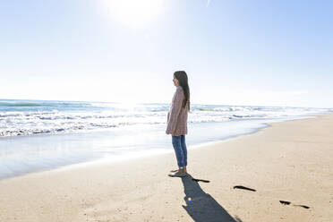 Mädchen schaut vom Strand aus auf den Horizont an einem sonnigen Tag - MEGF00075