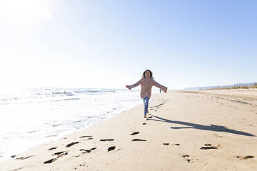 Glückliches Mädchen läuft am Strand an einem sonnigen Tag - MEGF00078