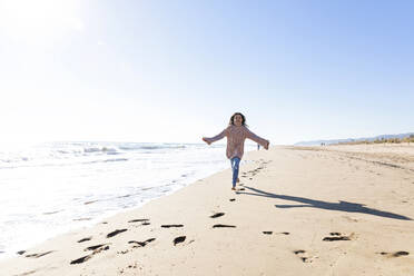 Happy girl running at beach on sunny day - MEGF00078