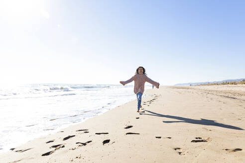 Happy girl running at beach on sunny day - MEGF00078