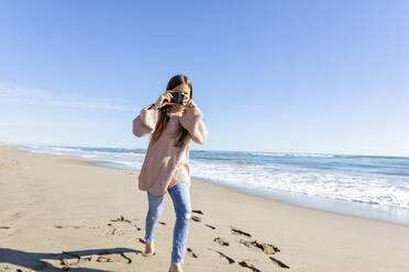 Mädchen läuft und klickt Fotos von der Kamera am Strand - MEGF00079