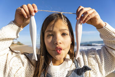 Mädchen mit künstlichem Fisch, der sich am Strand kräuselt - MEGF00094